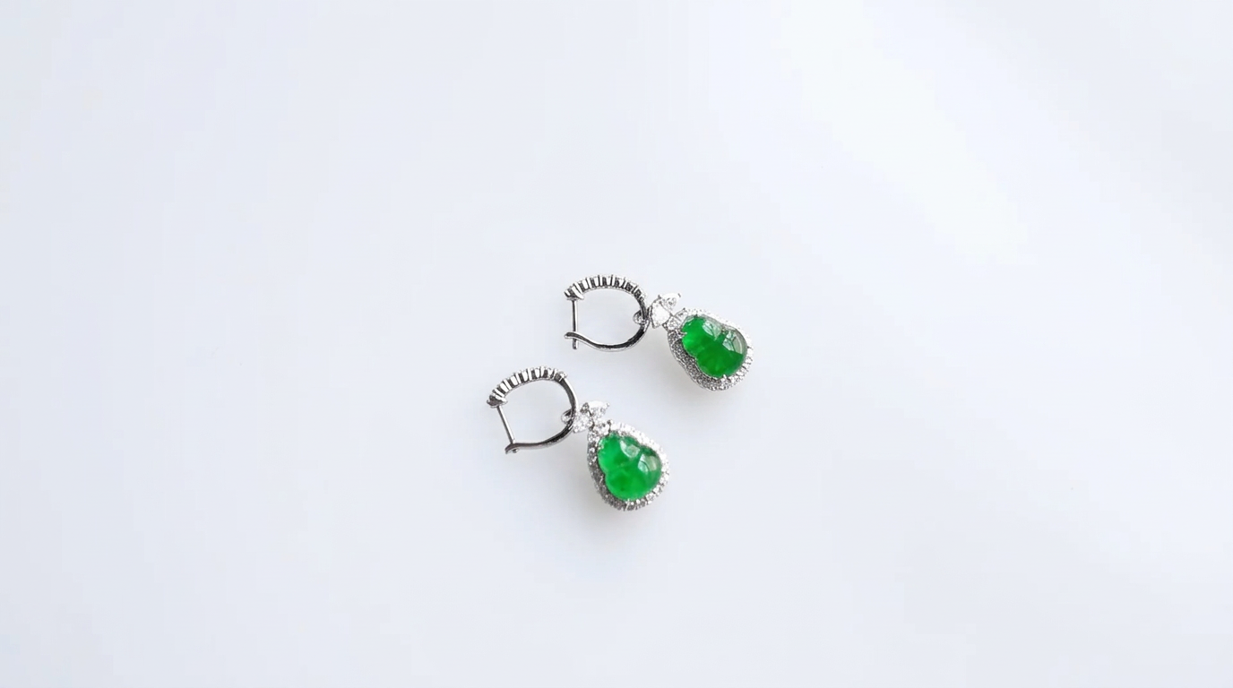 Pair of green jade gourd-drop earrings framed with brilliant-cut stones on a white background